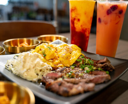 Food on plate top of table with two boba drinks on the side