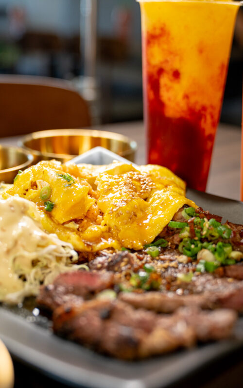 Food on plate top of table with two boba drinks on the side
