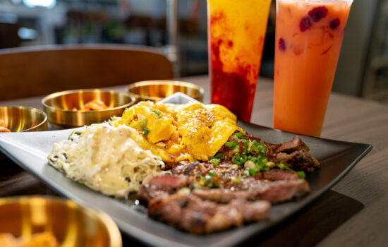 Food on plate top of table with two boba drinks on the side